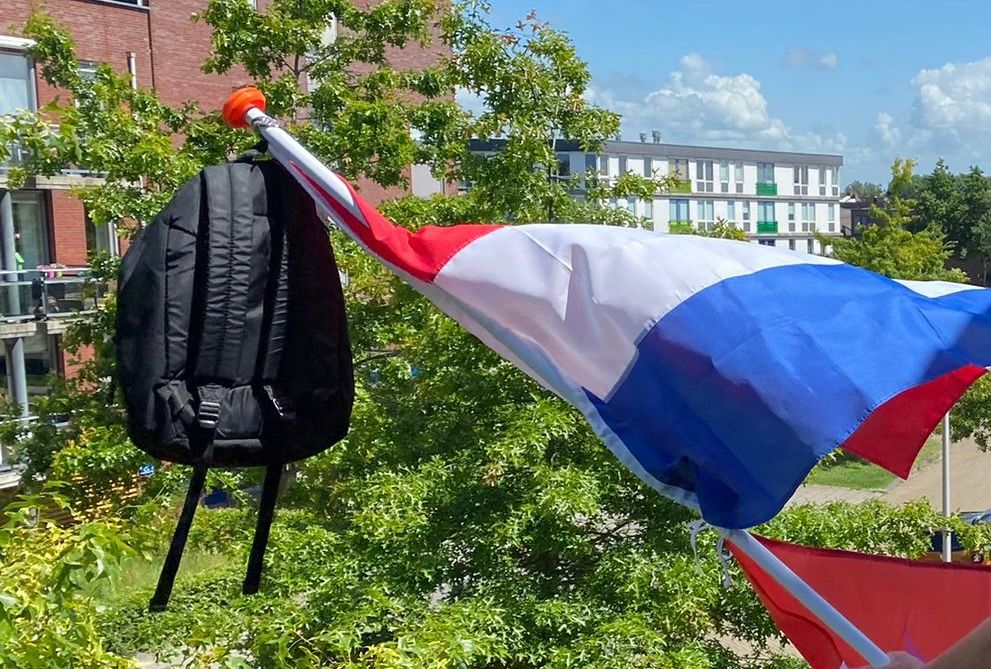 Afbeelding van een schooltas aan een vlaggenmast met wapperende vlag. In Nederland wordt in de tijd van de eindexamens vaak een vlag met schooltas aan de vlaggenmast gehangen om te vieren dat een leerling geslaagd is. Hierbij staat de tas symbool staat voor de last die van de schouders van de leerling valt nu hij of zij geslaagd is.